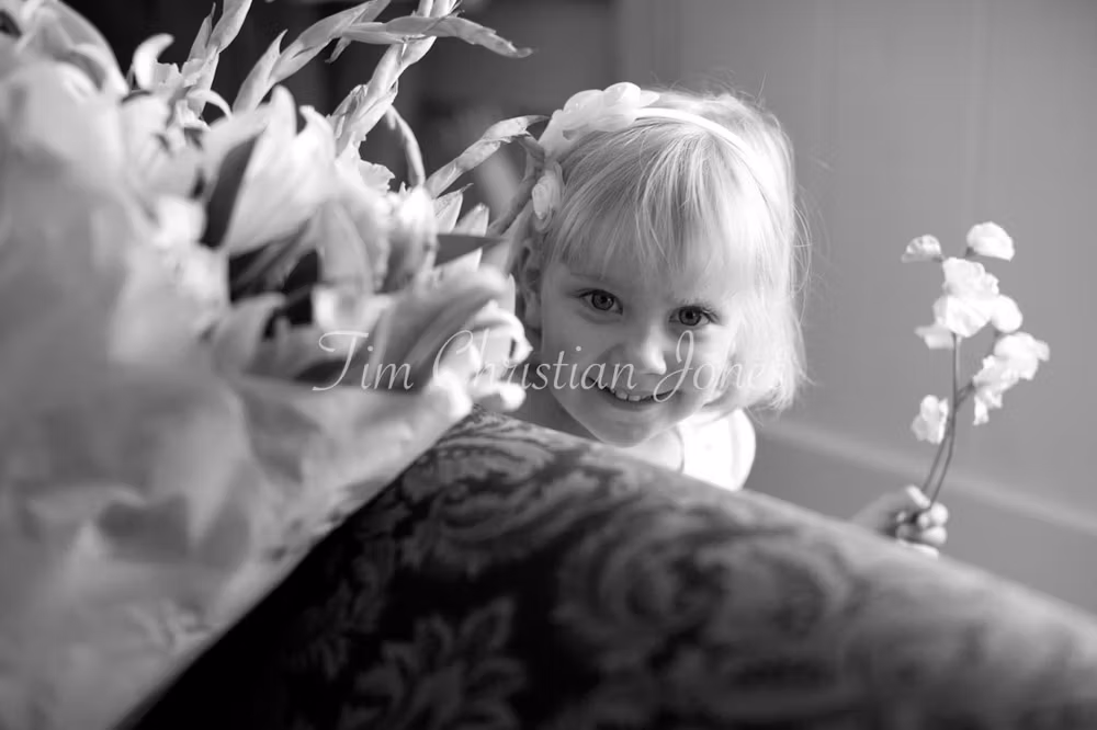 Bridesmaid peeps from the sofa holding her wedding flowers