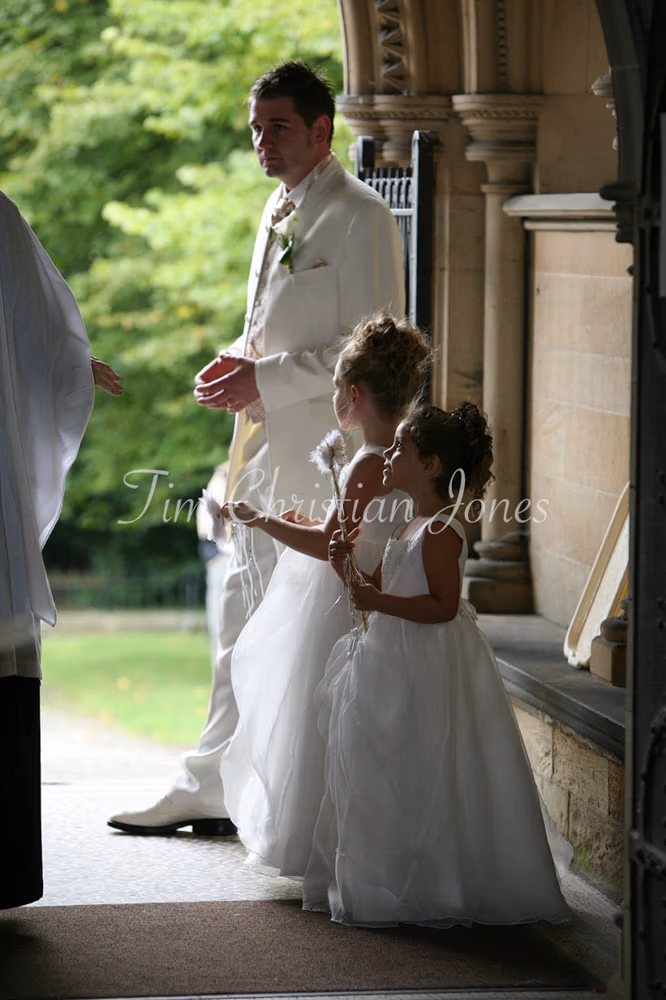 Groom looking pensive with his 2 bridesmaids talking to the Father