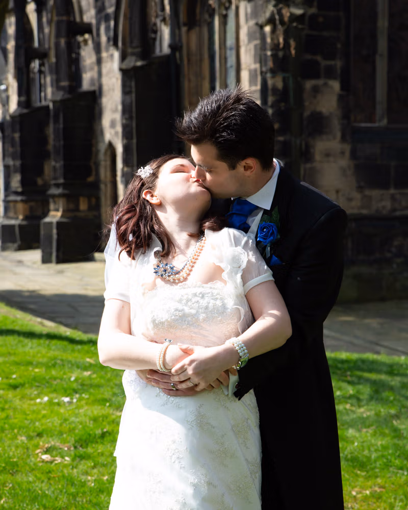 Claire and Tom share a quiet kiss on the steps of their wedding bus, captured in timeless black and white