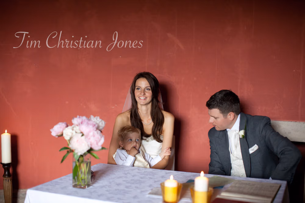 Couple at the signing table with their son, framed by red walls of the Temple of Apollo