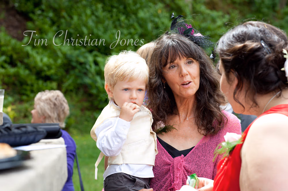 Wedding guests mingle outside in the sunshine after the ceremony