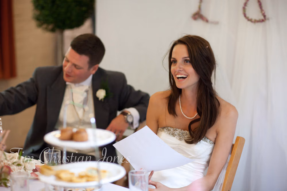 Lowri laughs and Tim covers his mouth, amused