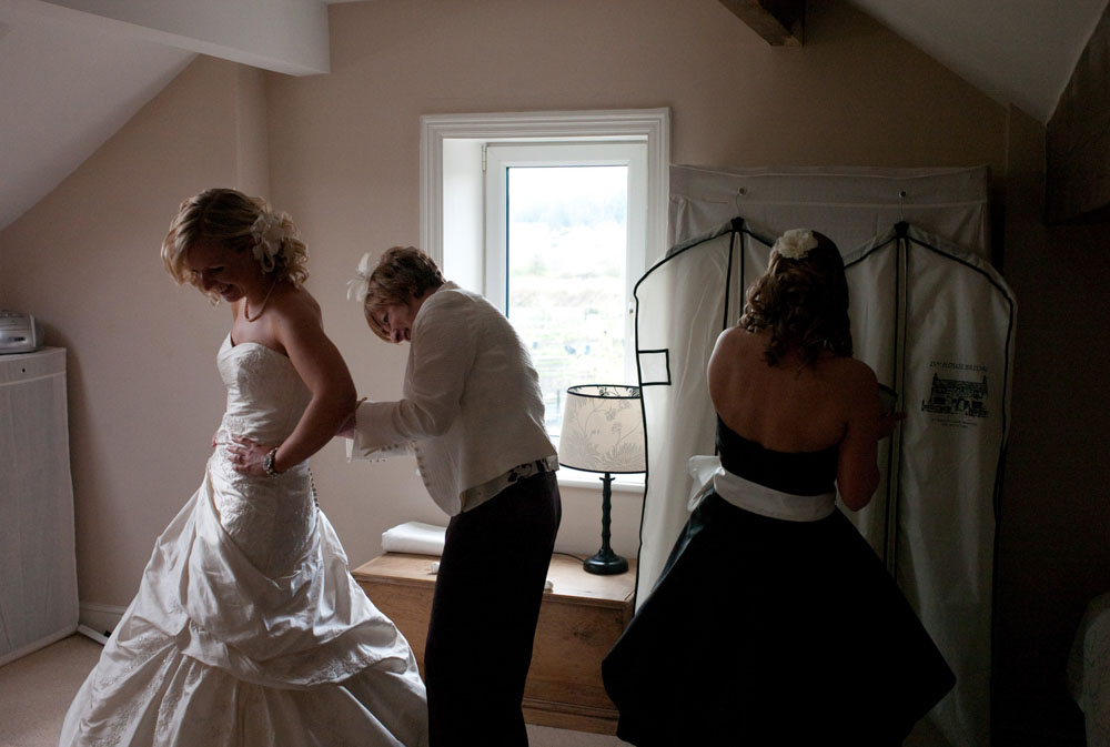 Mum helps Dani fasten the final buttons on her wedding dress