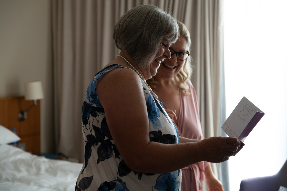 Clare’s mum smiles warmly while reading a congratulatory wedding card