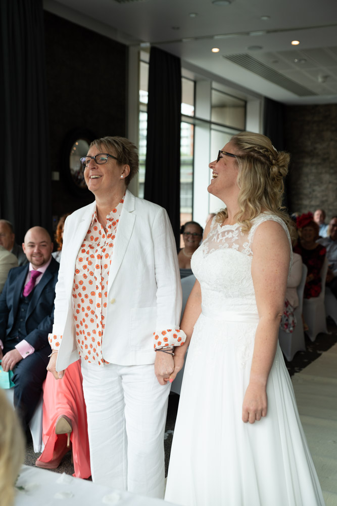 The couple holding hands as they arrive at the ceremony table