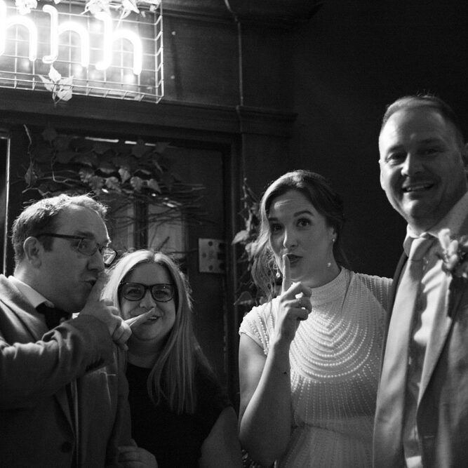 Couple and best man posing with a neon “shhh” sign at Lost & Found Leeds Club