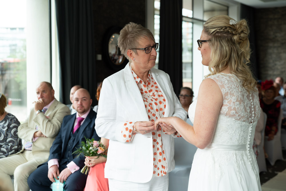 The couple holding hands as their vows continue
