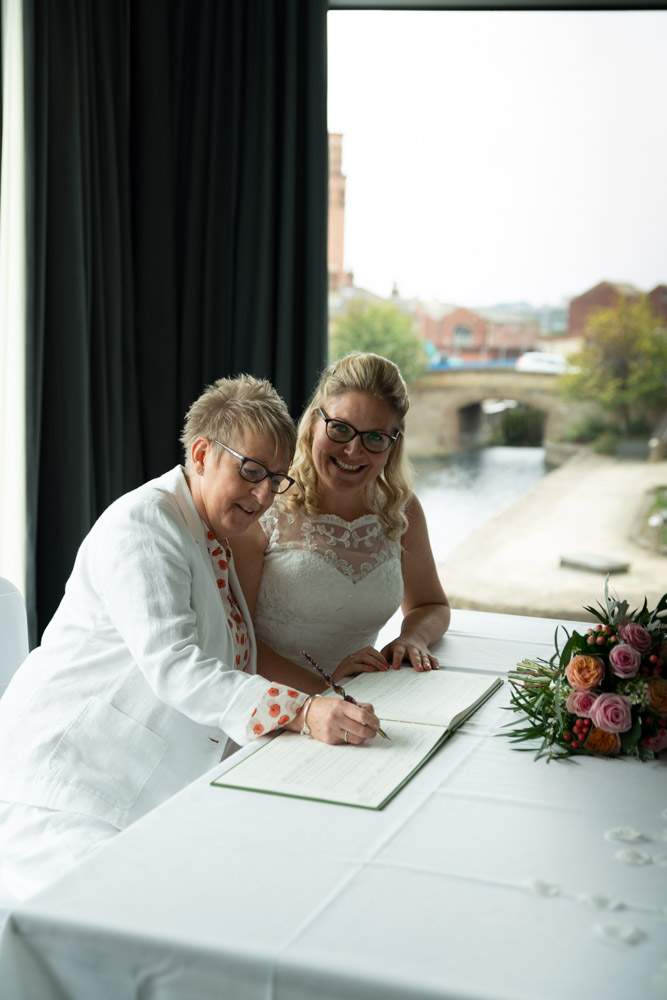 Tracey pretending to sign the register with a little smile