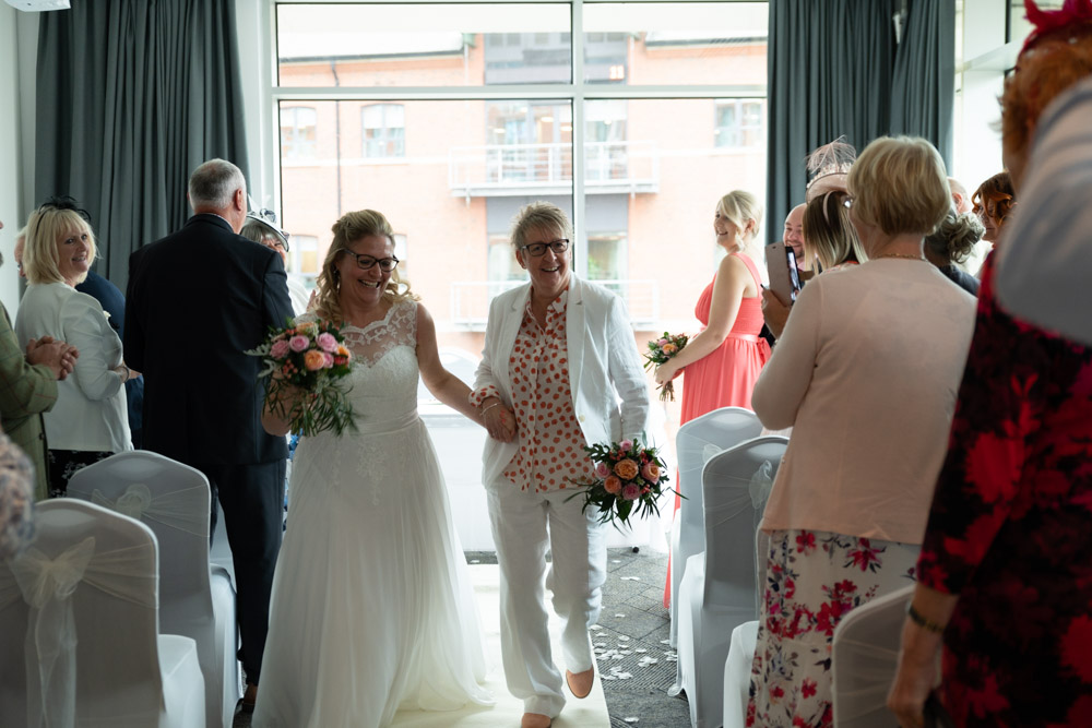 Clare and Tracey dancing joyfully down the aisle