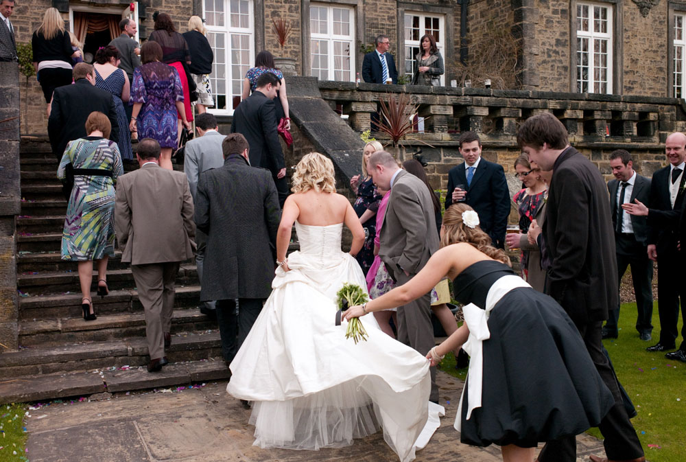 Bridesmaid helps adjust Dani’s dress as guests walk into the venue