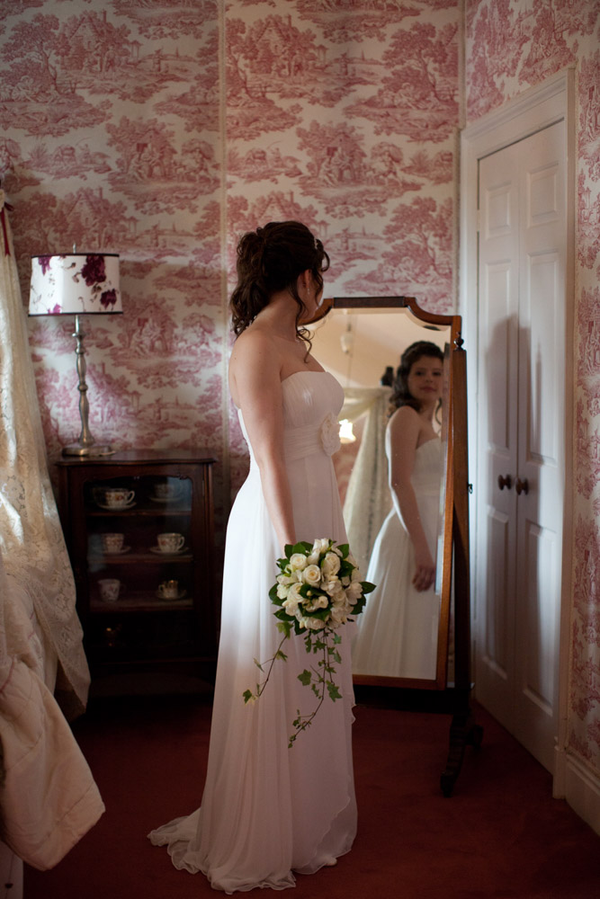 Bride standing near a tall mirror in the elegant Soughton Hall bridal suite