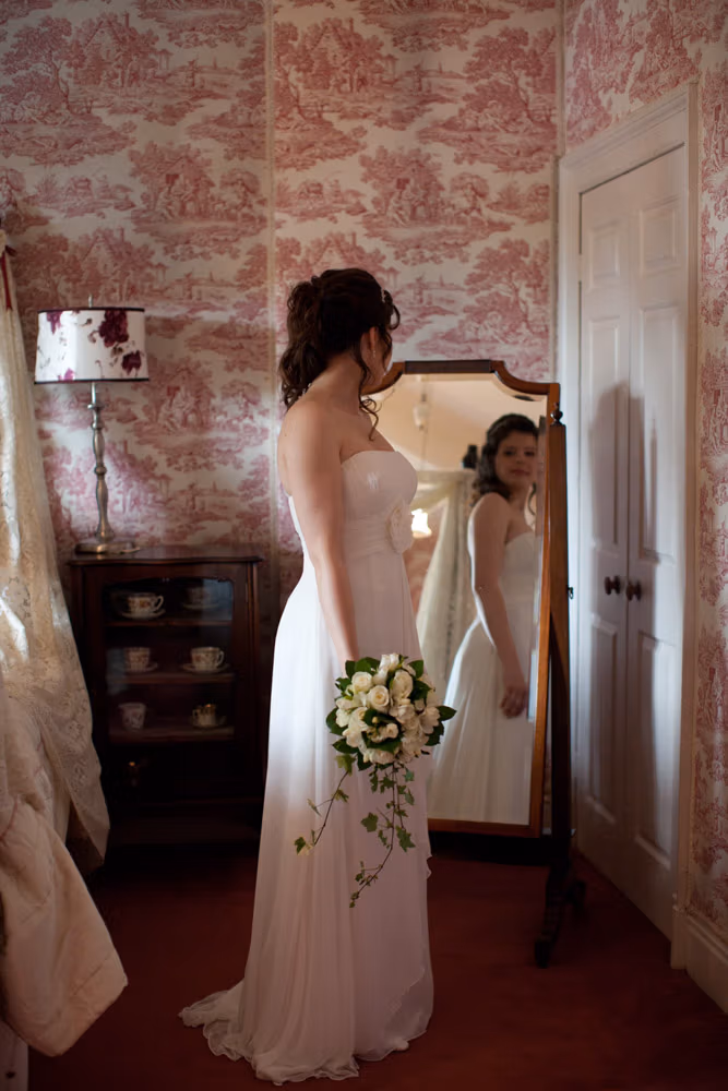 Bride standing near a tall mirror in the elegant Soughton Hall bridal suite