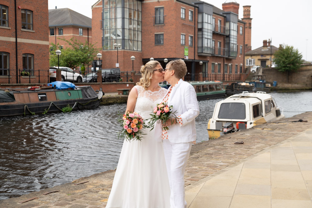 Clare and Tracey sharing a kiss by the waterfront