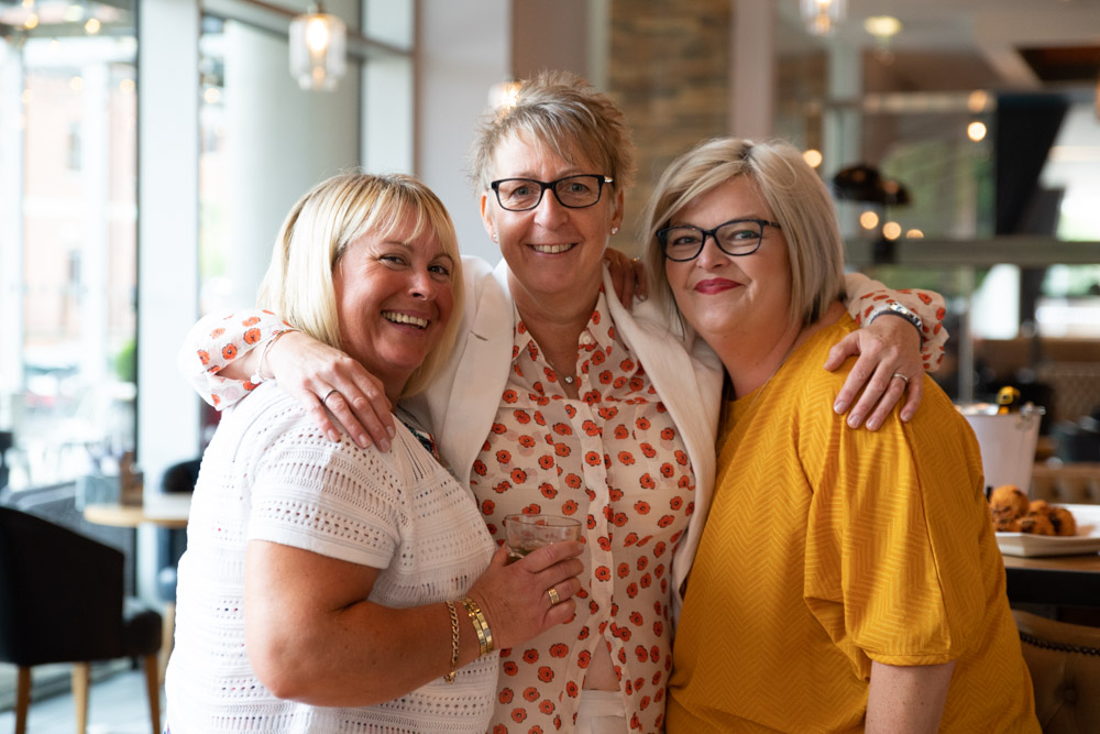 Tracey posing with arms around two friends