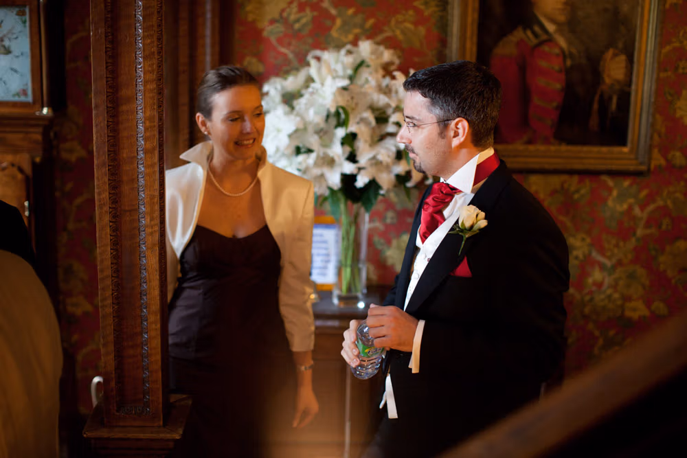 Groom in red cravat smiling and chatting with guests before the ceremony