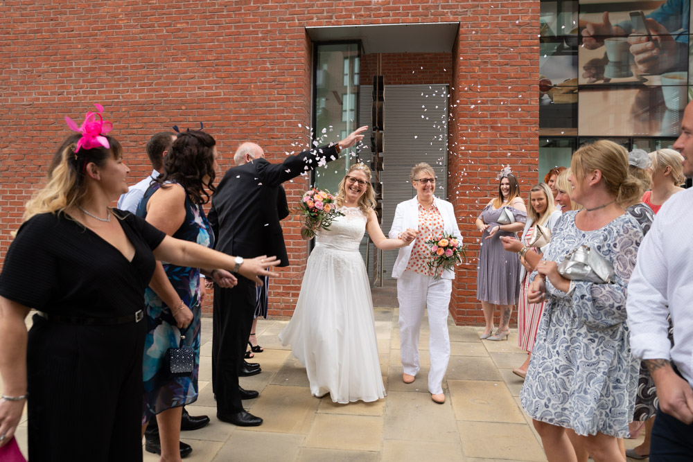 Clare and Tracey walking as confetti is thrown