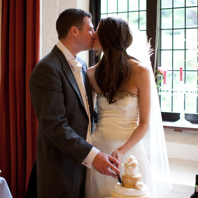 Lowri and Tim share a kiss while cutting their unique cheese layer wedding cake
