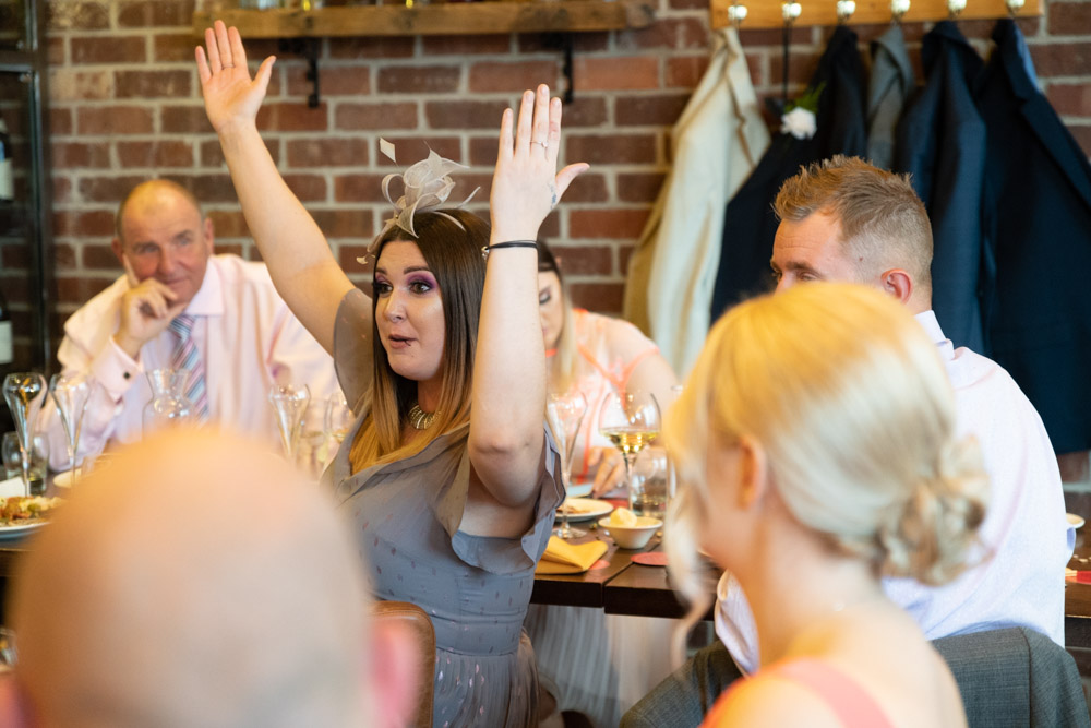 A guest raises her arms mid-laughter