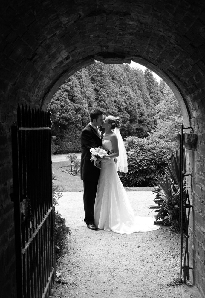 Classic black and white couple portrait taken through a stone tunnel.