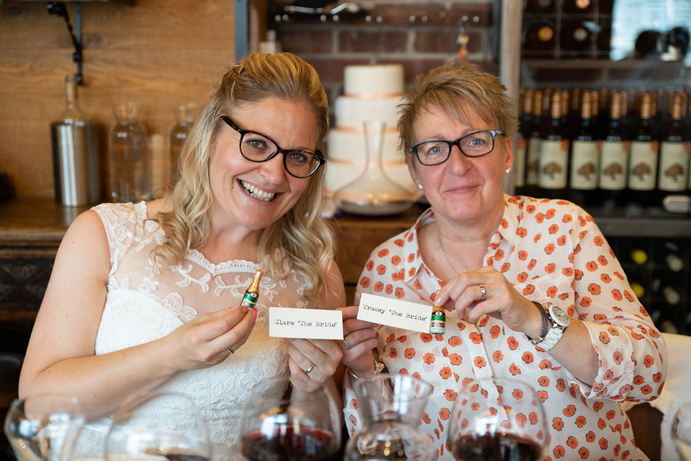 Clare and Tracey smiling with name cards and mini champagne bottles