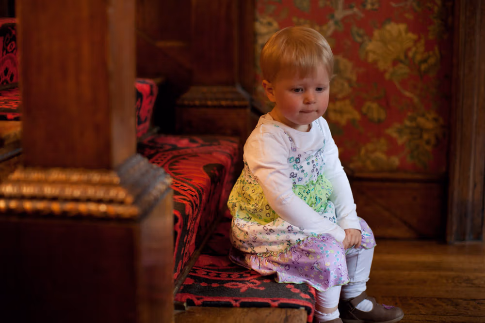 Young girl in a floral dress sitting quietly on a step before the ceremony