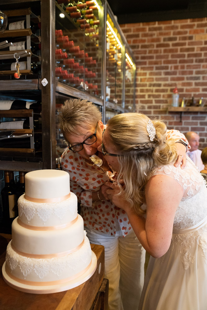 The couple leaning in to taste a slice of wedding cake