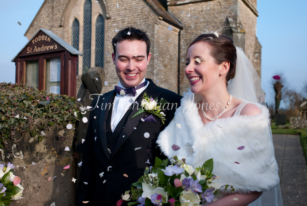 A closer shot of the couple outside the church, surrounded by confetti, their faces full of joy as petals fall.