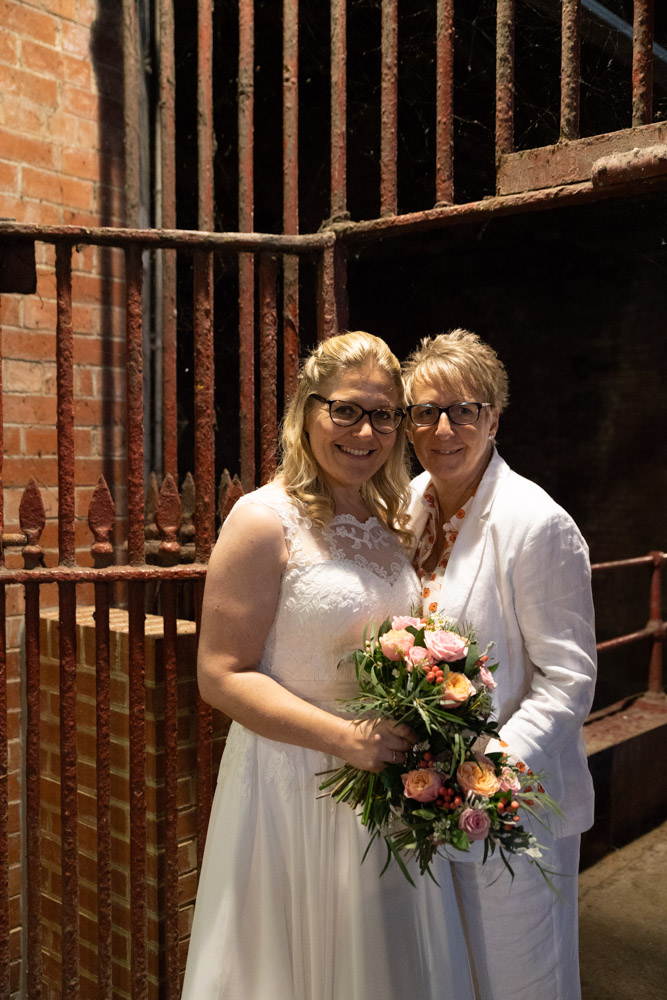 Close-up of the couple by the station gate with bouquets