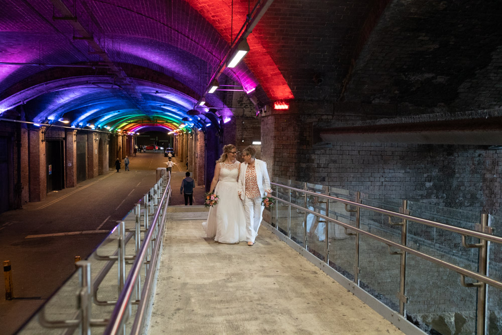 The couple walking hand in hand on the wooden tunnel walkway under Granary