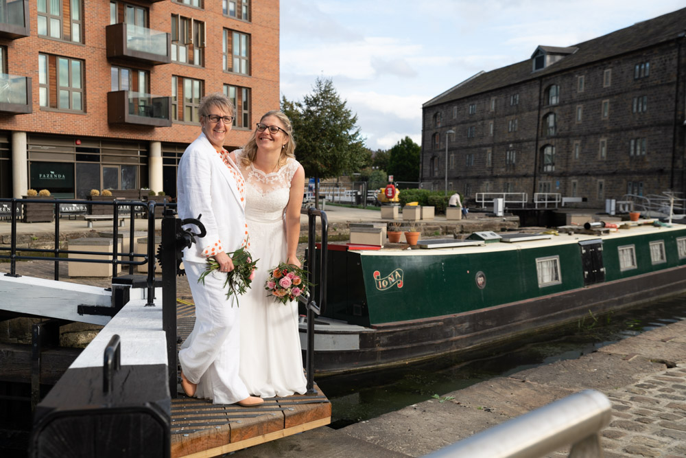 The couple on the lock with canal boats, buildings, and sky behind