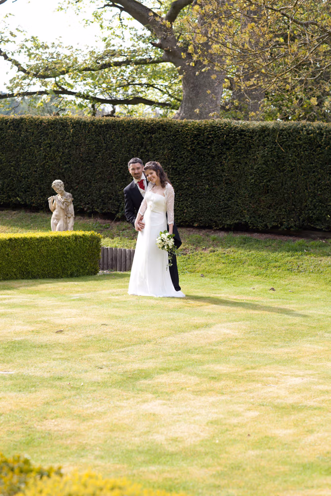 Couple leaning slightly away from each other on the green lawn in a fun pose