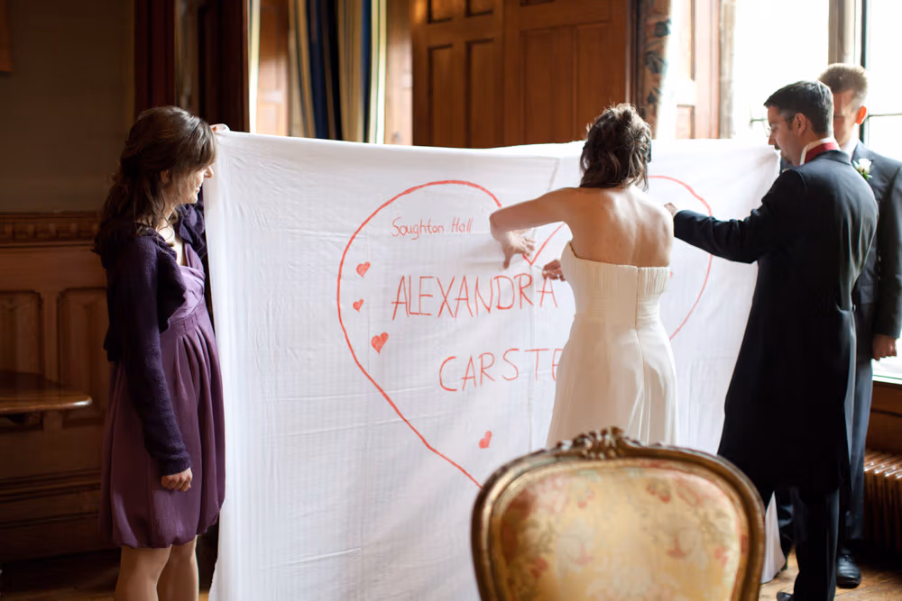 Bride and groom begin cutting the heart shape from the sheet together
