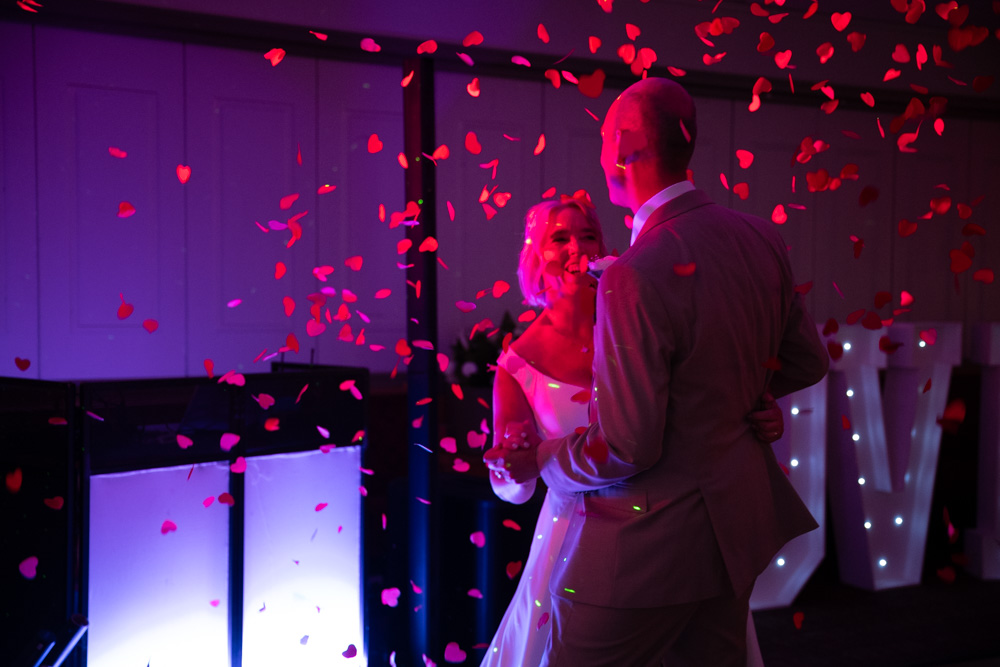 Bride and groom share their first dance under a shower of red heart confetti at the Leeds Irish Centre
