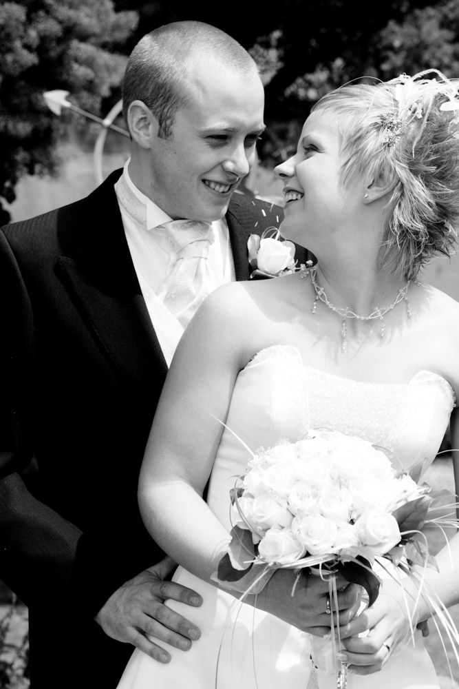 Black and white portrait of a smiling couple, eye to eye in a quiet moment — captured by a Leeds wedding photographer.
